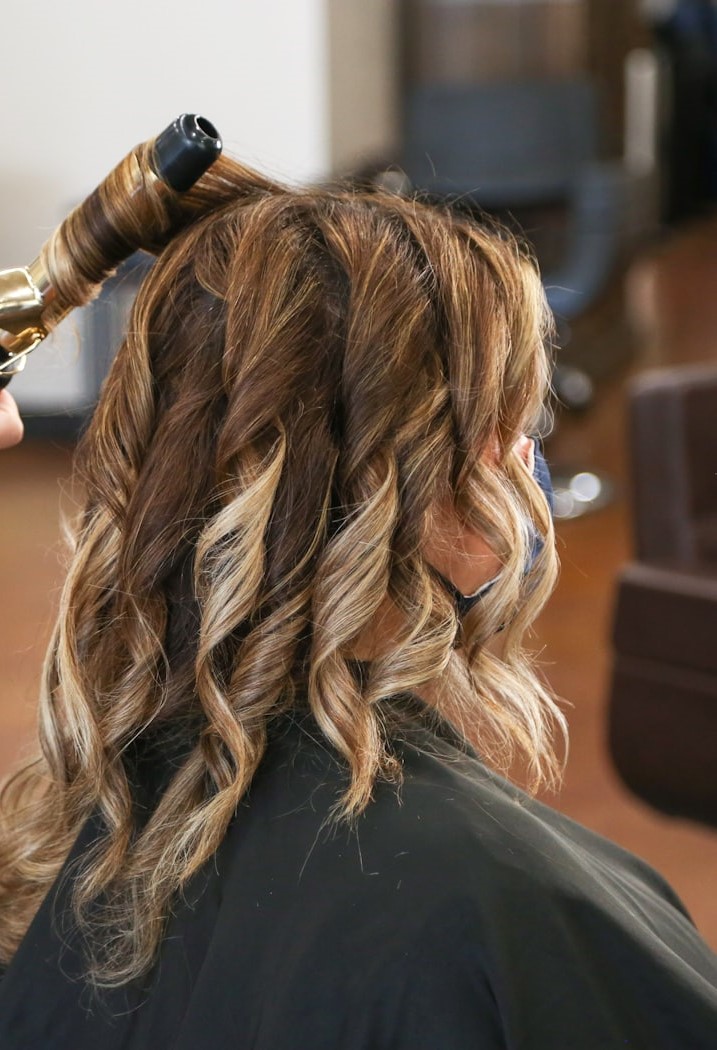 Marli, cabeleireira com 29 anos de experiência, modelando o cabelo de uma cliente no salão em Pouso Alegre